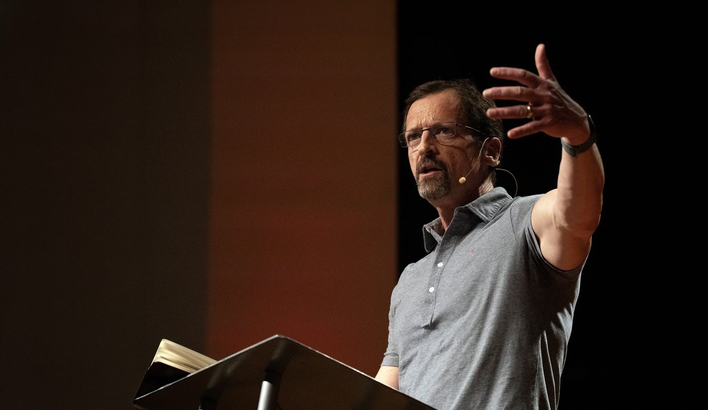 Dan Cruver preaching, open Bible in hand